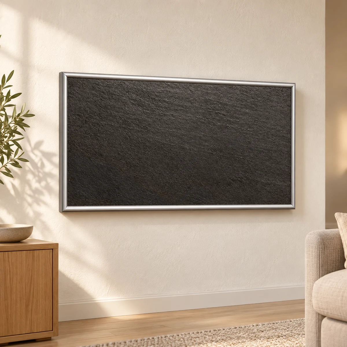 Anthrazitfarbene Infrarot-Keramikheizung mit silbernem Rahmen an einer hellen Wand.